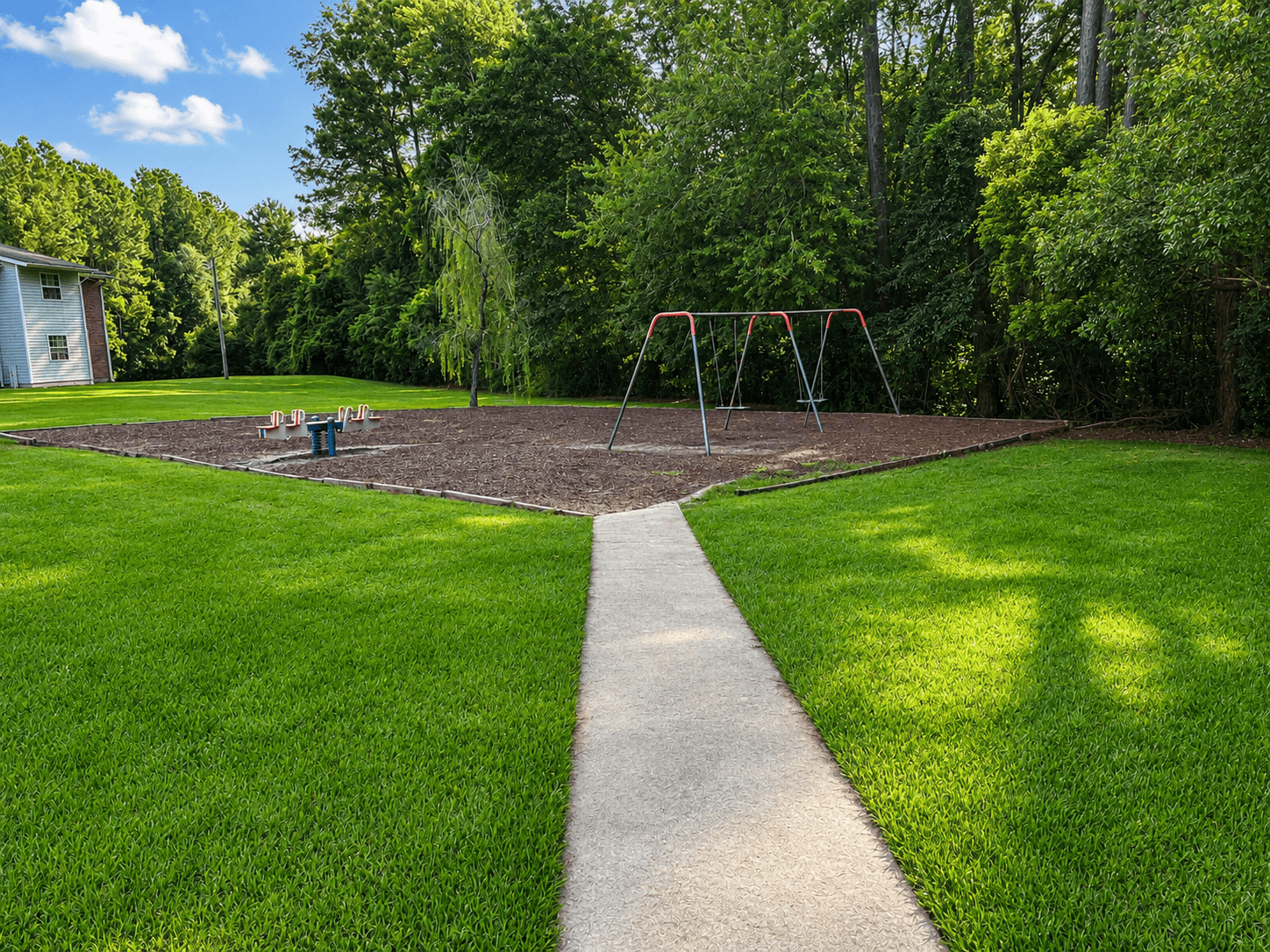 A playground with a swing set in the middle of a grassy area.